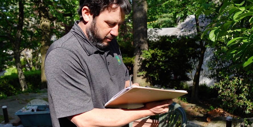 An Almstead arborist writing up a property inspection report